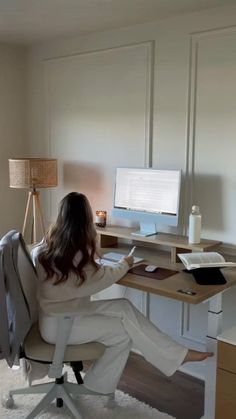 a woman sitting at a desk in front of a computer on top of a wooden desk