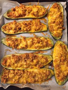 several stuffed zucchini boats on a baking sheet with cheese and meat toppings