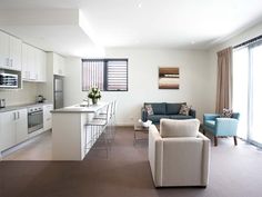 a living room filled with furniture next to a kitchen