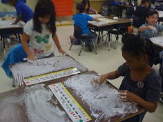 two children are playing with letters and numbers on a sheet of plastic in a classroom