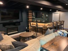 a living room filled with furniture and a flat screen tv mounted to the wall next to a bar