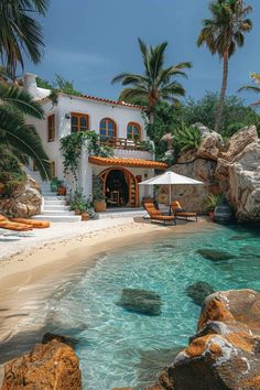 a house sitting on top of a sandy beach next to the ocean with palm trees