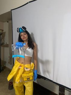 a woman in yellow pants and white top posing for the camera with a plastic bag on her hip