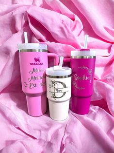 three different colored tumblers sitting next to each other on a pink bed sheet with the words, i love my mom and me