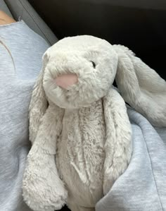 a white stuffed rabbit sitting on top of a person's lap in a car