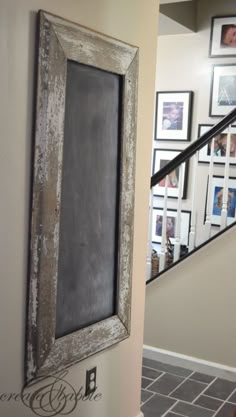 an old framed chalkboard is hanging on the wall next to a stair case in a home