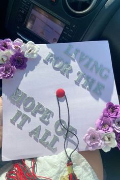 someone is holding up a graduation cap with flowers on it