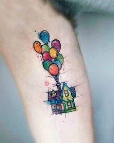 a house with balloons tattoo on the side of its leg and it's legs