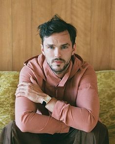 a man sitting on top of a couch wearing a pink hoodie and brown pants