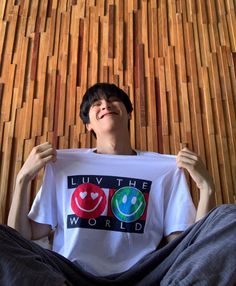 a man sitting on the floor holding up a t - shirt that says livt the world