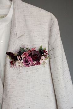 a white jacket with flowers and leaves on the lapel, attached to a buttonhole