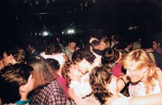 a crowd of people standing around each other at a concert or party with lights on