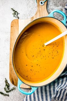 a pot filled with soup on top of a wooden cutting board