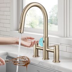 a person washing their hands under a kitchen faucet