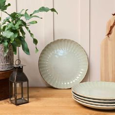 three plates sitting on top of a wooden table next to a potted green plant