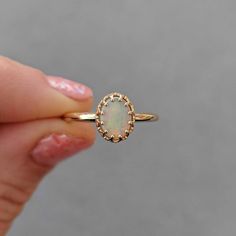 This antique style crown ring comes with a gorgeous Australian oval opal. If you want a different stone or want to add accent diamonds contact us for a quote. Details: - Default stone size is 7x5mm Australian Opal in oval shape. - Shiny finish by default. - Default width is 1.8mm at the bottom and 8.7x6.5mm at the top - Default thickness is 1.6mm at the bottom and 2mm at the top. - Contact us for quote if you want to customize this ring in any way. Thank you for shopping with Sevgi Jewelry! 14k Gold Oval Cabochon Opal Ring For Anniversary, Elegant Opal Cluster Ring, Heirloom 14k Gold Opal Ring Oval Cabochon, Elegant 14k Gold Oval Opal Ring, Elegant Oval Opal Ring In 14k Gold, 14k Gold Opal Ring With Halo Setting, Elegant Opal Cabochon Promise Ring, Elegant Opal Promise Ring With Cabochon, Oval Opal Ring With Halo Setting In 14k Gold