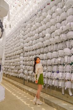 a woman standing in front of a large amount of white objects