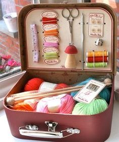 an open suitcase filled with yarn and knitting needles on top of a window sill