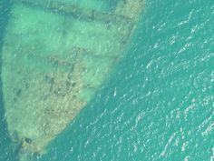 an aerial view of the ocean with a ship wreck in the middle of the water