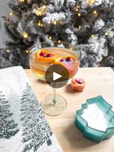 a table topped with a glass filled with liquid next to a christmas tree