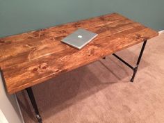 a laptop computer sitting on top of a wooden table next to a blue painted wall