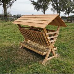 a wooden structure with hay in it on the grass