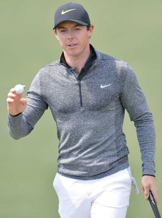 a man holding a tennis racquet on top of a green field with a ball in his hand