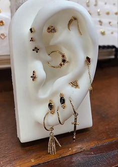 a pair of earring and ring sitting on top of a wooden table next to a white sculpture