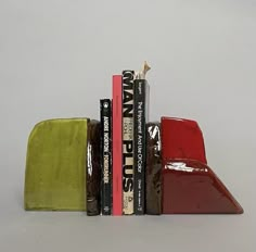 three books are stacked on top of each other in front of a gray background and one is red