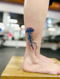 a jellyfish tattoo on the foot of a person's leg with purple ink