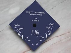 a blue graduation cap with white birds on it that says i have turned from what if fall to what if fly