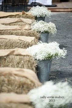 hay bales are lined up on the ground with baby's breath flowers in them