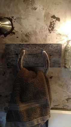 a brown towel hanging on a wooden hook in a bathroom with a light above it