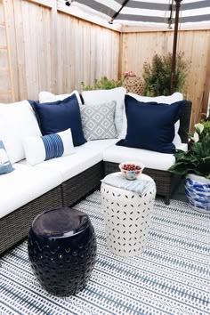 a white couch sitting on top of a blue and white rug next to a wooden fence