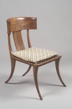 a wooden chair with a cushion on the seat and backrest, against a gray background