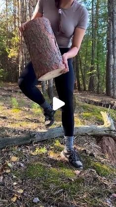 a woman holding a large piece of wood in the woods