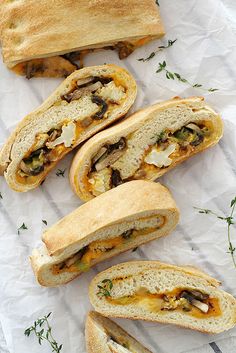 several sandwiches cut in half and stacked on top of each other with cheese, mushrooms, and herbs