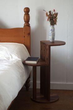 a bed with a white comforter and a wooden side table next to the bed