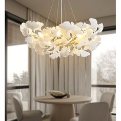 a white chandelier hanging from a ceiling in a room with chairs and table