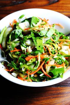 a white bowl filled with salad on top of a wooden table