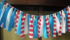 red, white and blue streamers are hanging from a wooden pole in front of a wall