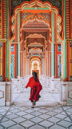 a woman in a red dress is walking through an ornate building