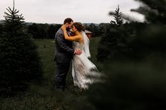 a bride and groom kissing in the middle of a field surrounded by christmas tree trees