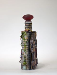 a brick tower with plants growing out of it's top, and a red bowl on top