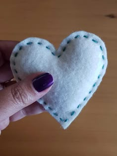 a hand holding a small white felt heart