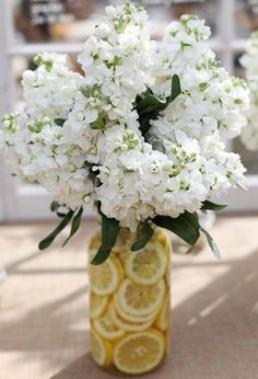 a yellow vase filled with white flowers and lemon slices