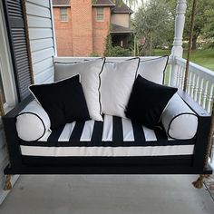 a black and white porch swing with pillows on it