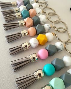 many different colored beads and tassels on a keychain with metal rings