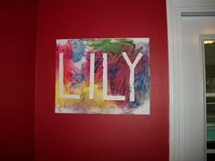 a red wall with a painting on it and the words lilly written in large letters