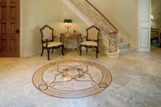 a foyer with marble flooring and chandelier next to two chairs under a stair case